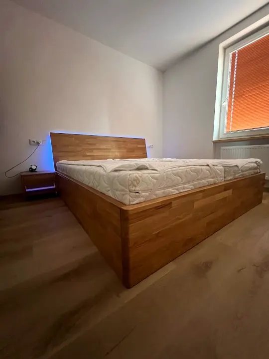 Masivní postel v ložnici